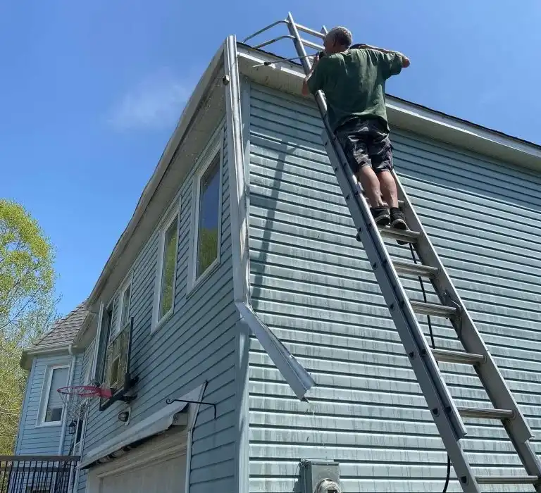eavestrough installer fitting seamless gutters on a Barrie roofline